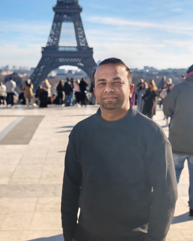 Arslan Azhar Sheikh in Paris with the Eiffel Tower behind him